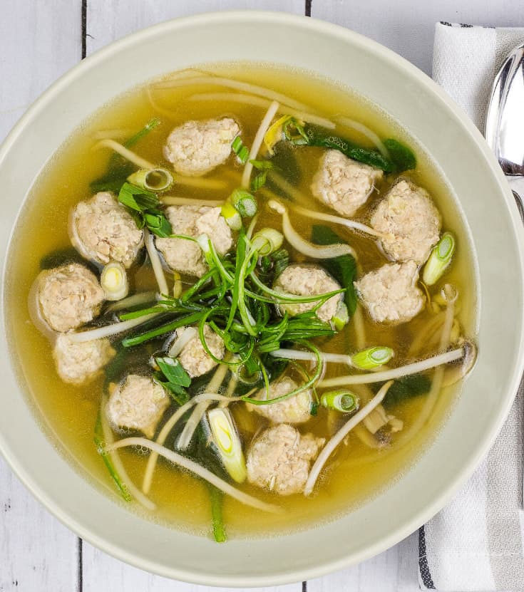 A bowl of Keto Wontonless Soup on a white wooden table.