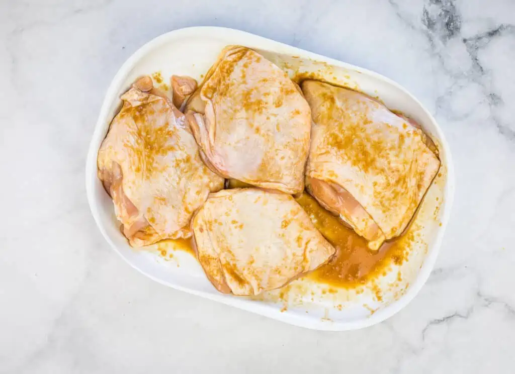 Raw chicken coated with sauce on a plate.