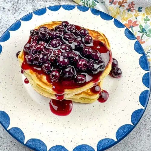 A stack of Blackstone Buttermilk pancakes with blueberry syrup on a plate.