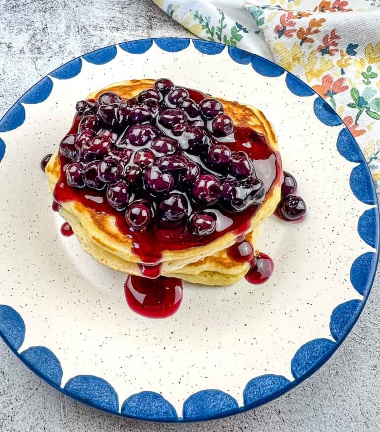 A stack of Blackstone Buttermilk pancakes with blueberry syrup on a plate.
