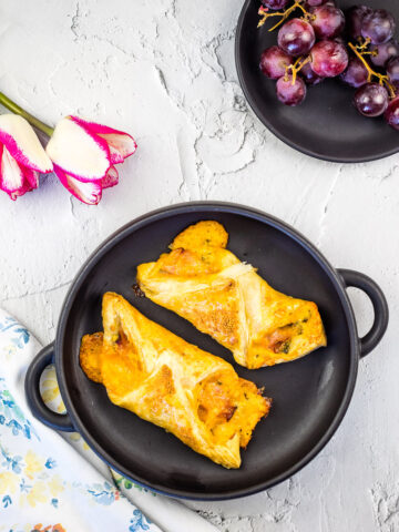 Ham and cheese turnovers on a black plate.