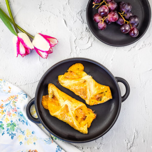 Ham and cheese turnovers on a black plate.