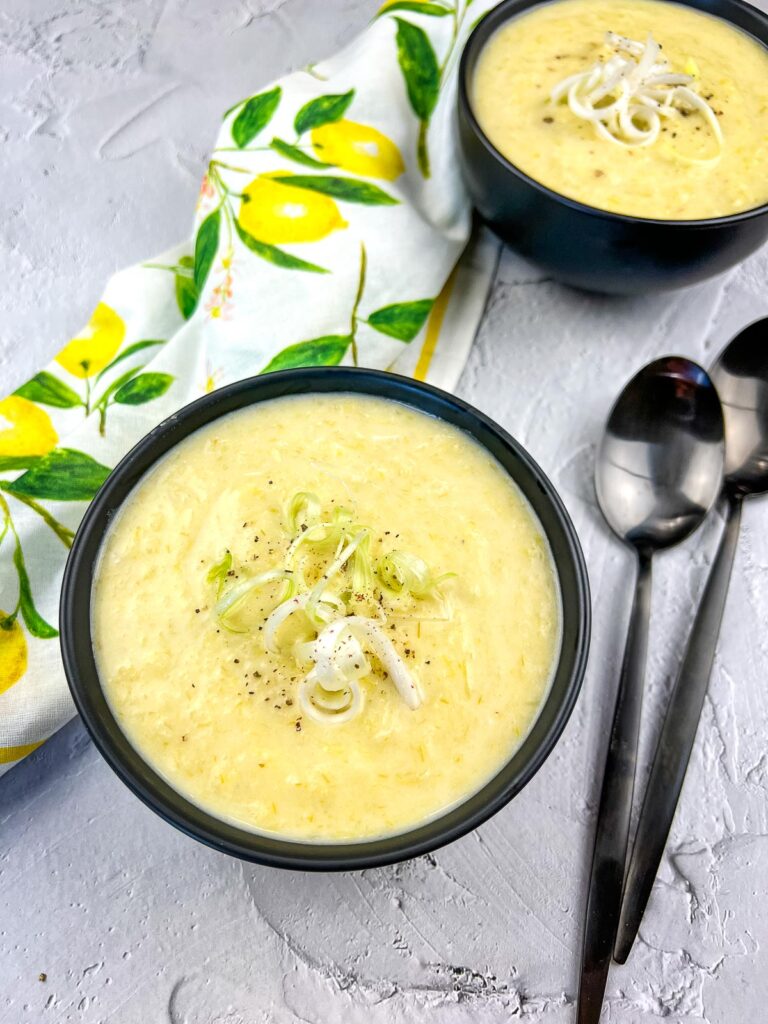 Leek and Green Garlic Soup in two black bowls with spoons.