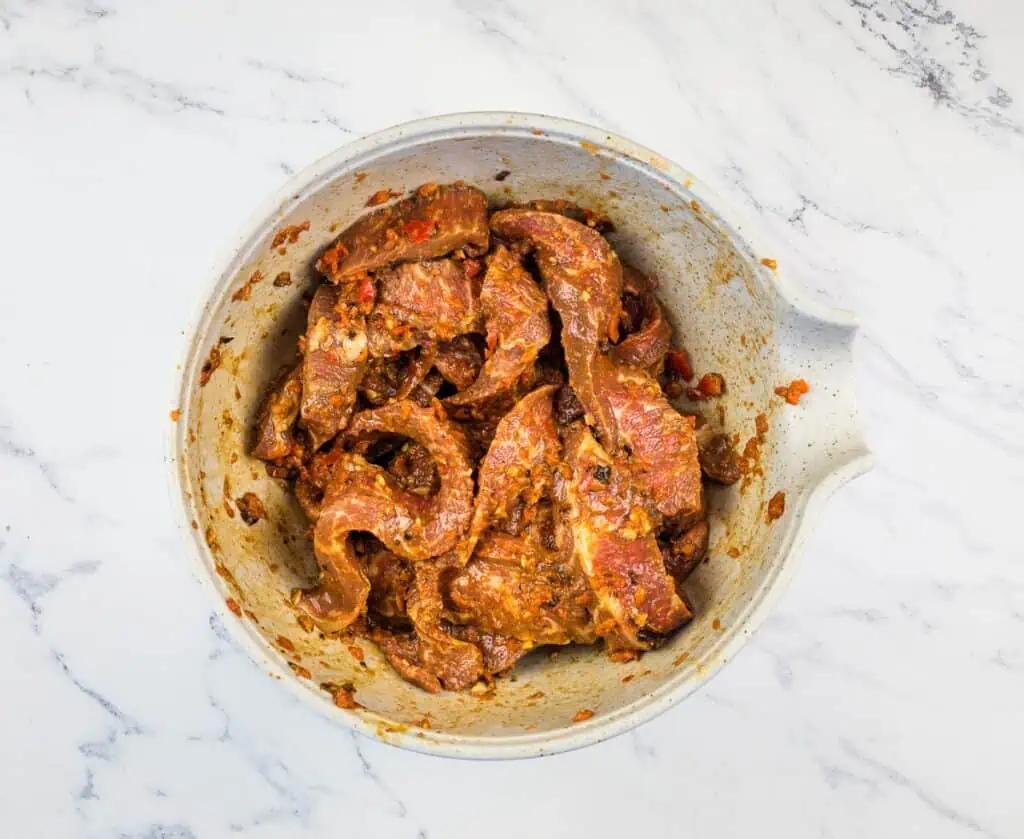 Steak marinating in a bowl.