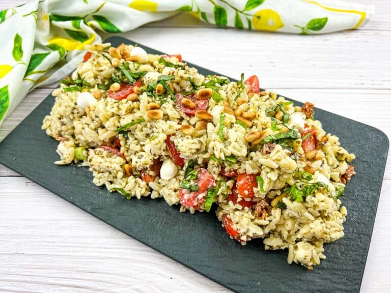 A plate of pesto orzo salad with tomatoes and pine nuts.