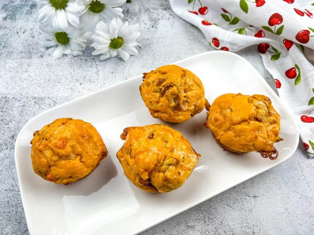 A top down horizontal shot of 4 pizza muffins on a white plate.