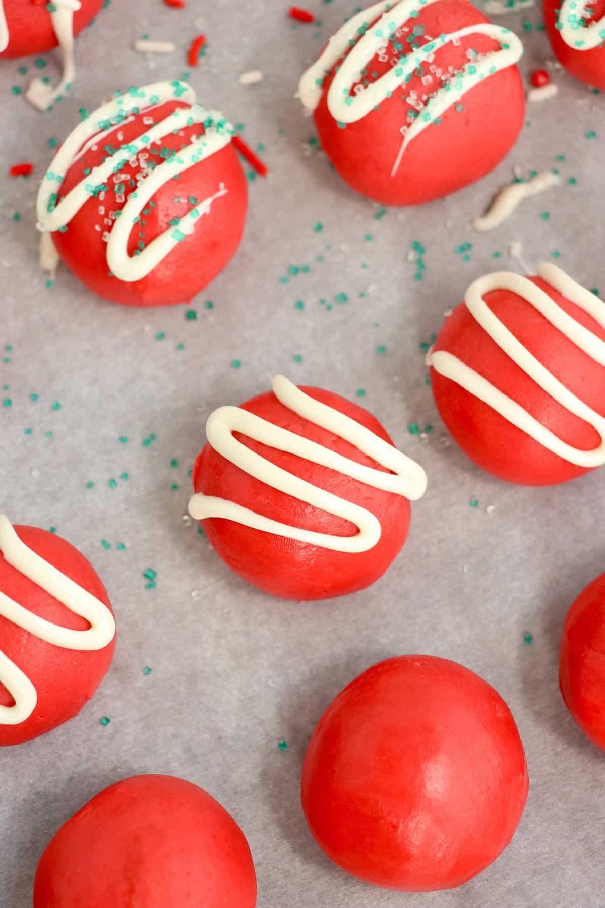 Decorated red velvet Christmas truffles on a sheet pan.