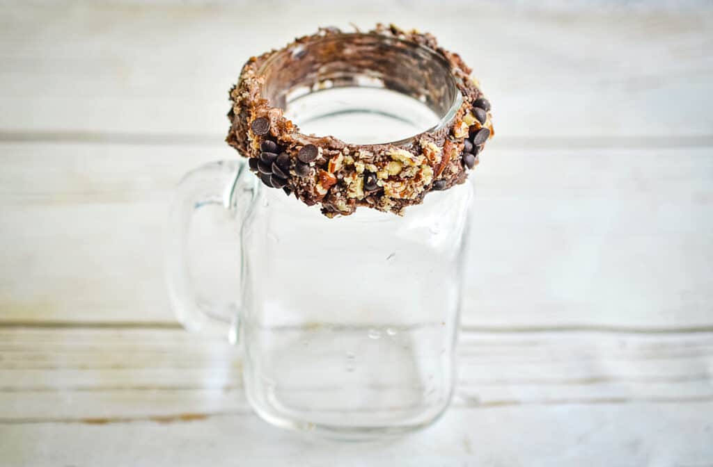 The rim of the glass rolled in nuts and chocolate chips.