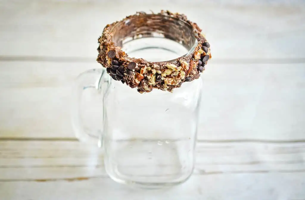 The rim of the glass rolled in nuts and chocolate chips.