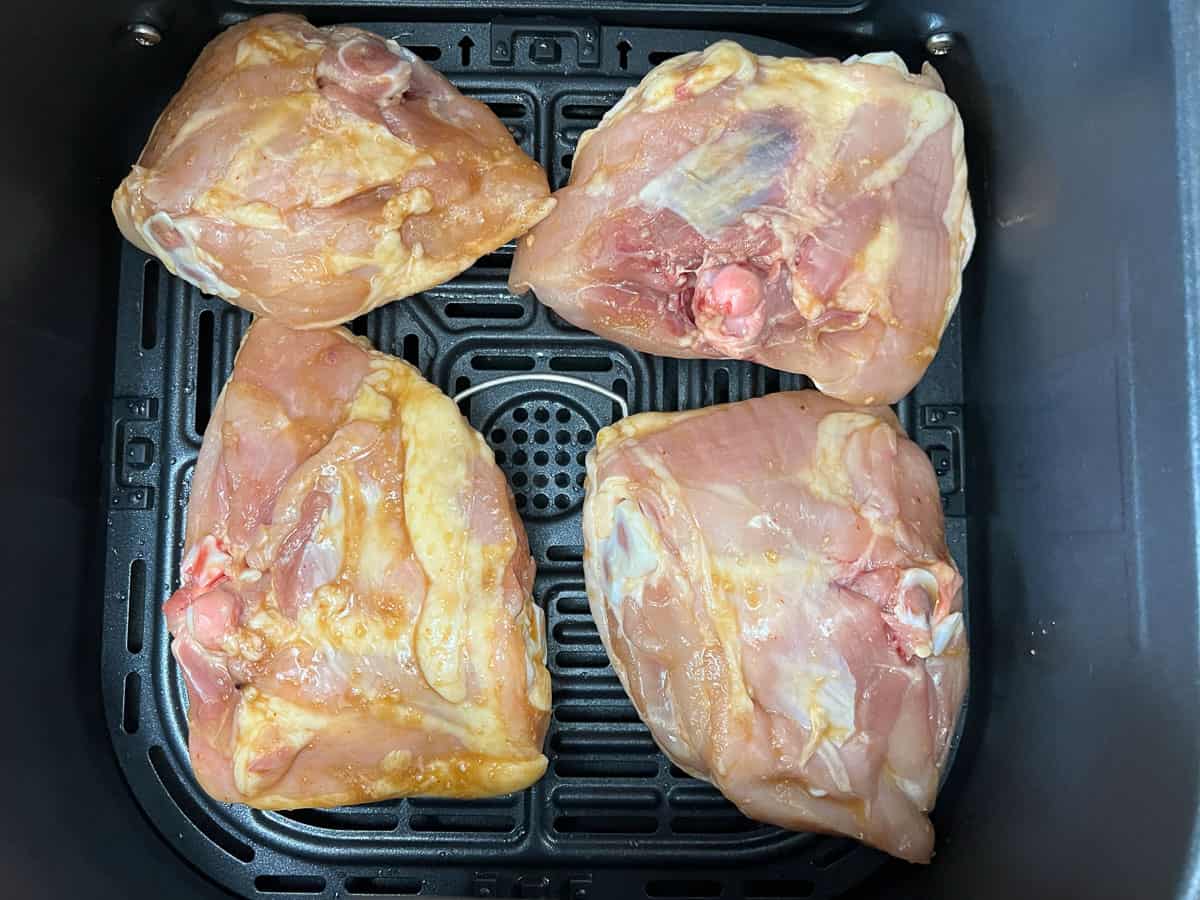 Chicken skin side down in an air fryer basket.