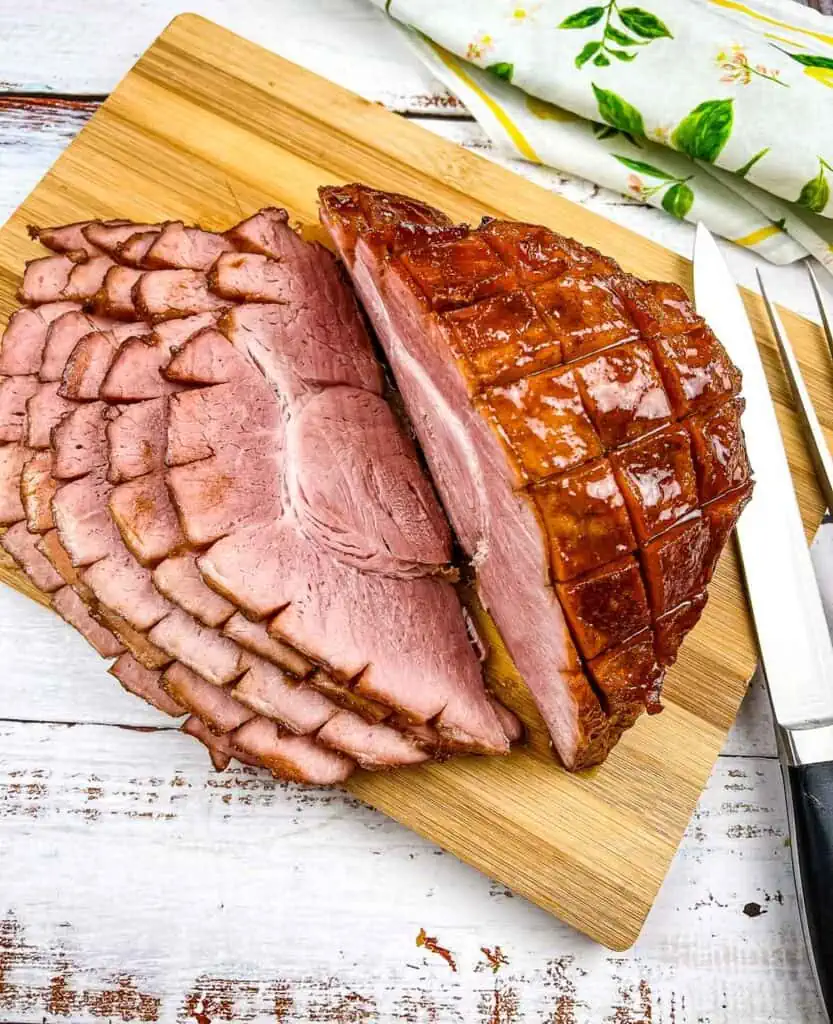 Sliced Smoked Carver Ham on a cutting board with a knife.