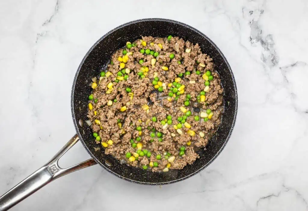 Peas and corn added to filling in the skillet.