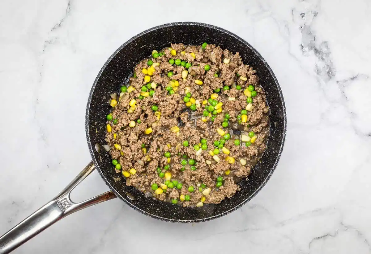 Peas and corn added to filling in the skillet.