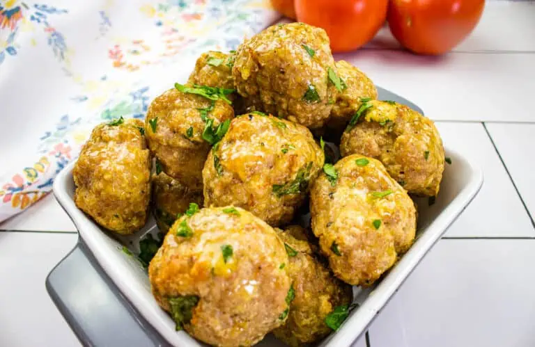 Meatballs in a white bowl with herbs.