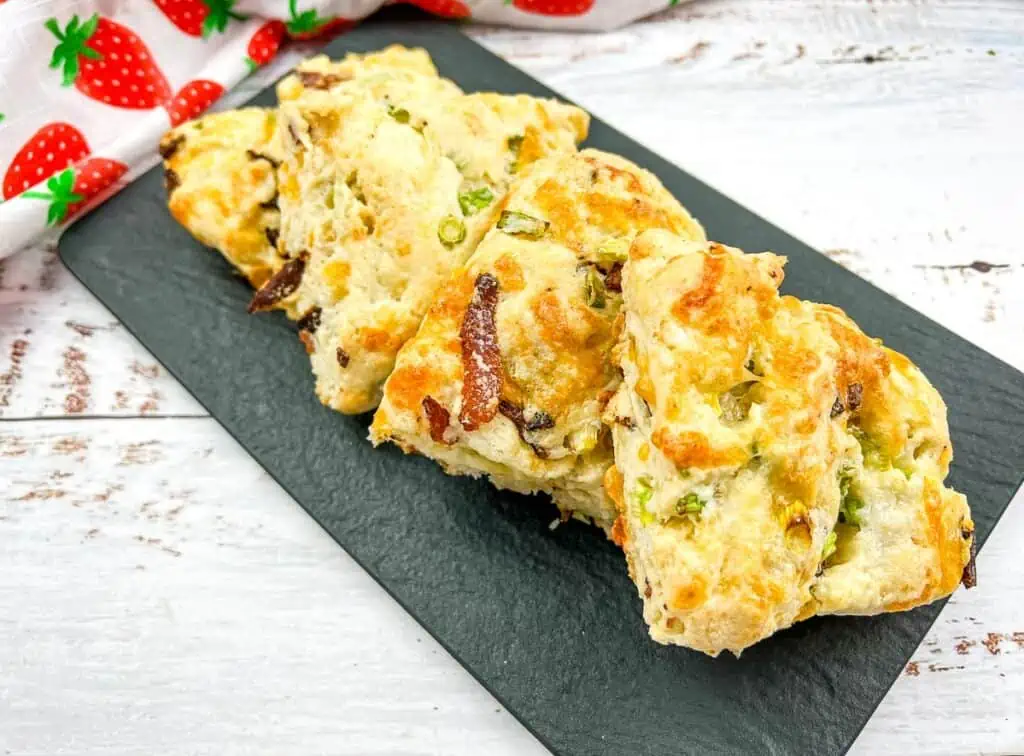 Bacon, cheddar, green onion biscuits on a black platter.