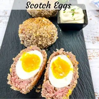 Baked Scotch Eggs on a black platter.