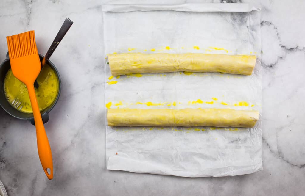 Fully rolled un-cut sausage rolls brushed with egg wash.