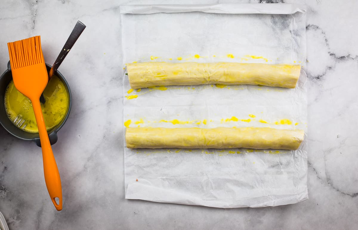 Fully rolled un-cut sausage rolls brushed with egg wash.
