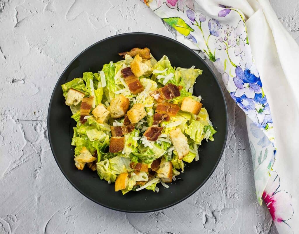 Caesar salad on a black serving dish.
