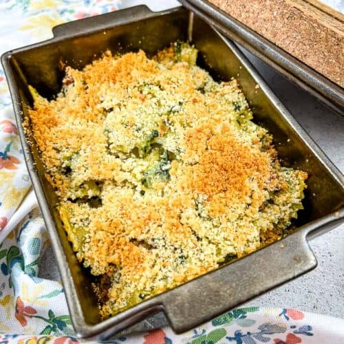 Chicken Florentine Artichoke Bake in a casserole dish with lid nearby.