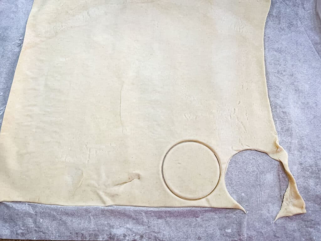 Puff pastry with some circles cut out of it.