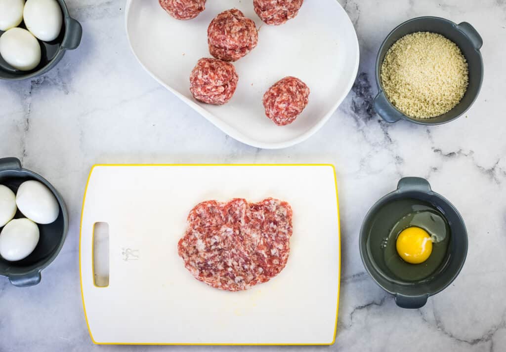 Flattened sausage ready to wrap the egg.