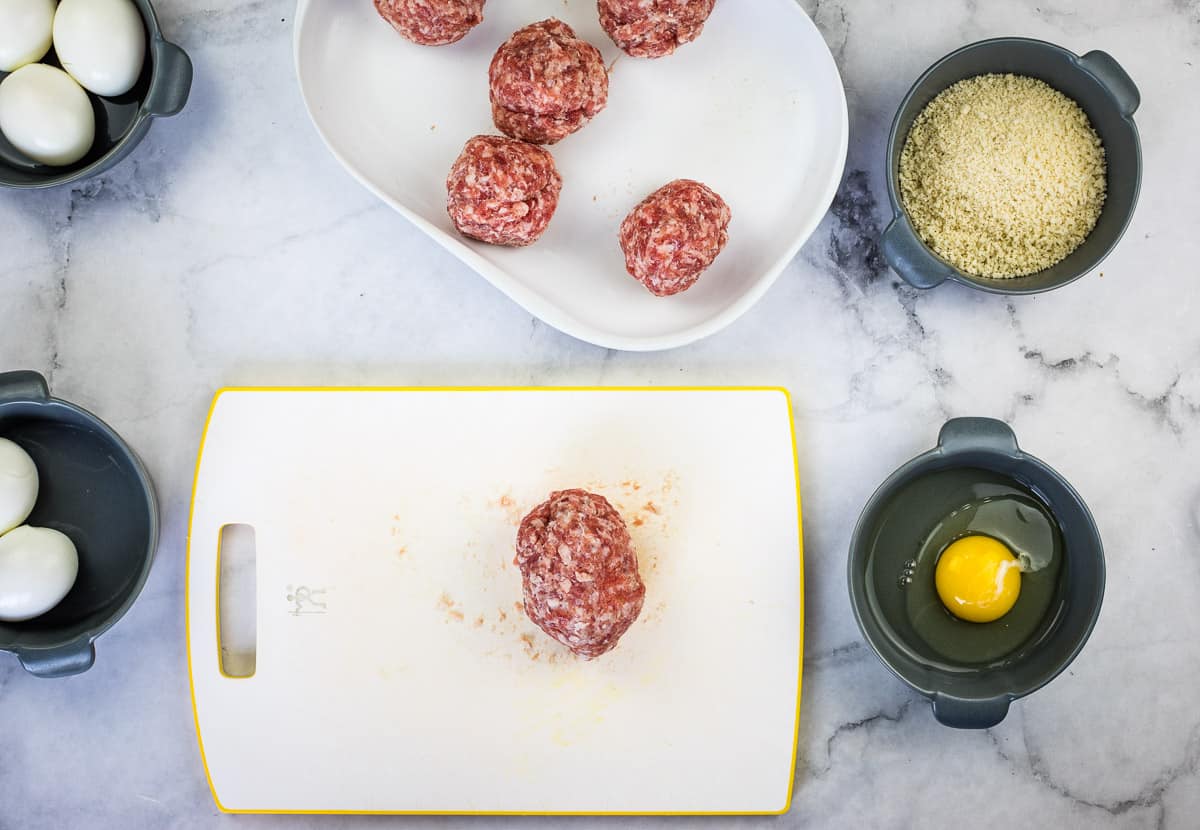 A sausage wrapped egg on a cutting board.