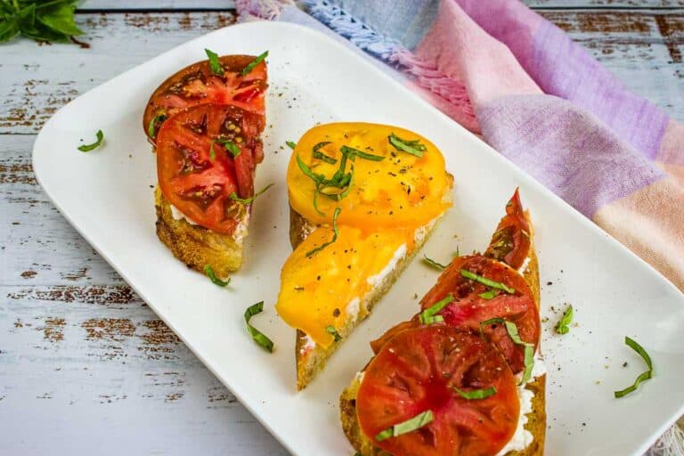 Three slices of grilled bread with tomatoes and ricotta on a plate.