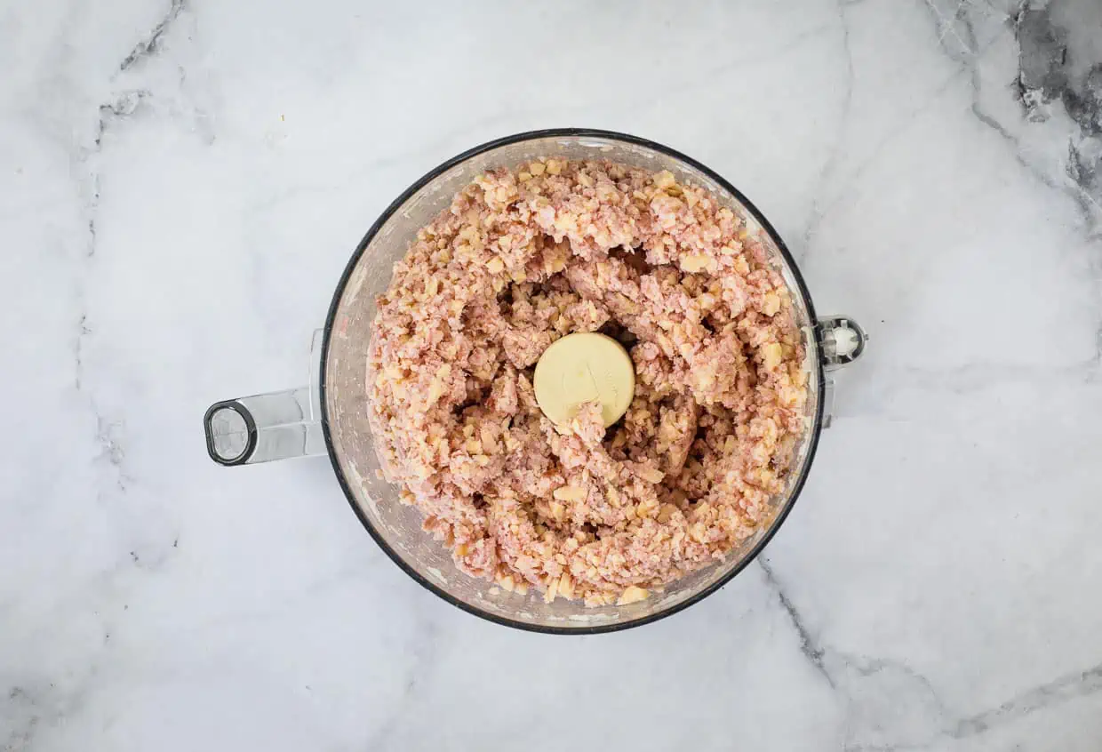 Ham, cheese, and onion in a food processor bowl.