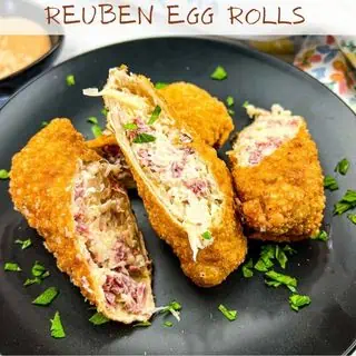 Reuben egg rolls on a black plate.