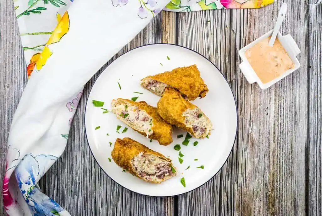 Reuben egg rolls on a white plate.