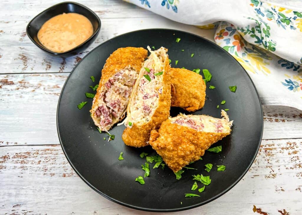 Reuben egg rolls on a black plate.