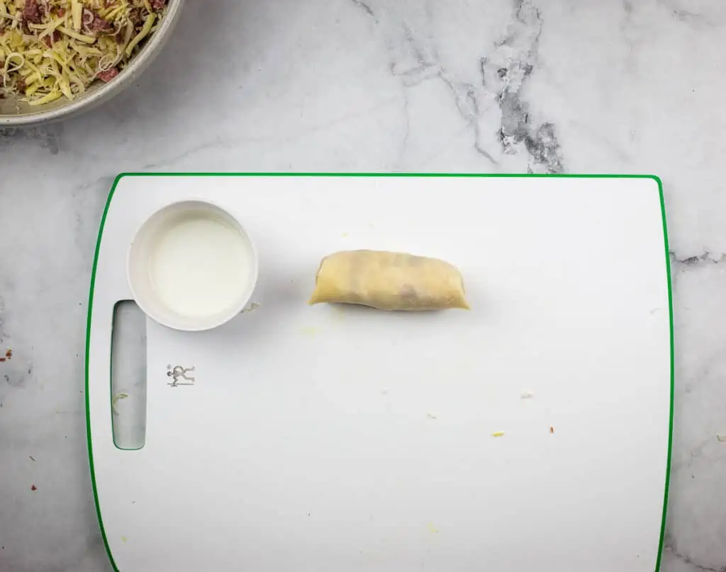 A rolled egg roll on a work surface.