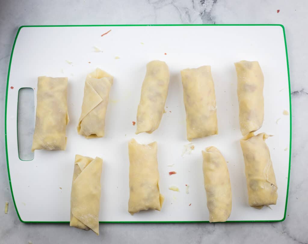 Rolled egg rolls lined up ready for frying.
