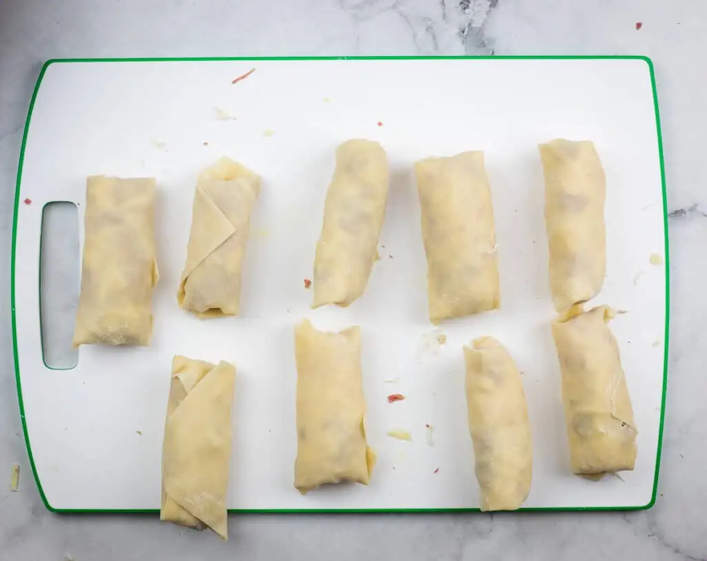 Rolled egg rolls lined up ready for frying.