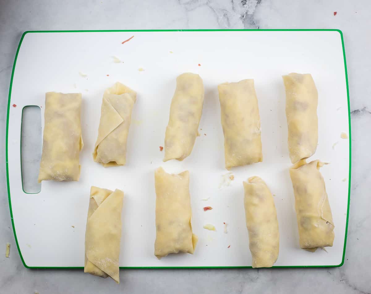 Rolled egg rolls lined up ready for frying.