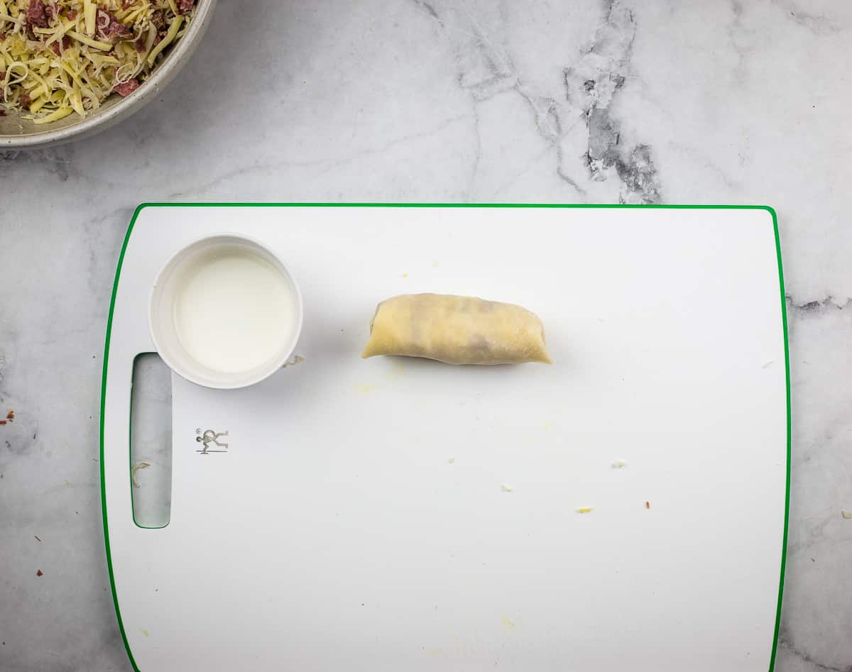 A rolled egg roll on a work surface.