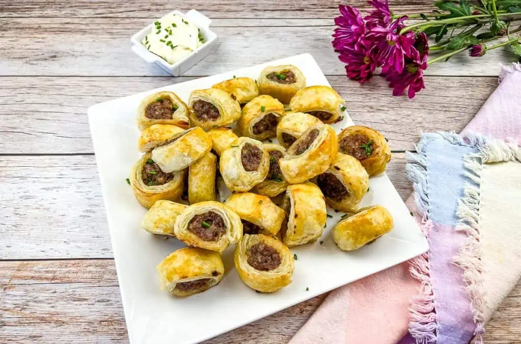 A plate of sausage rolls on a wooden table.