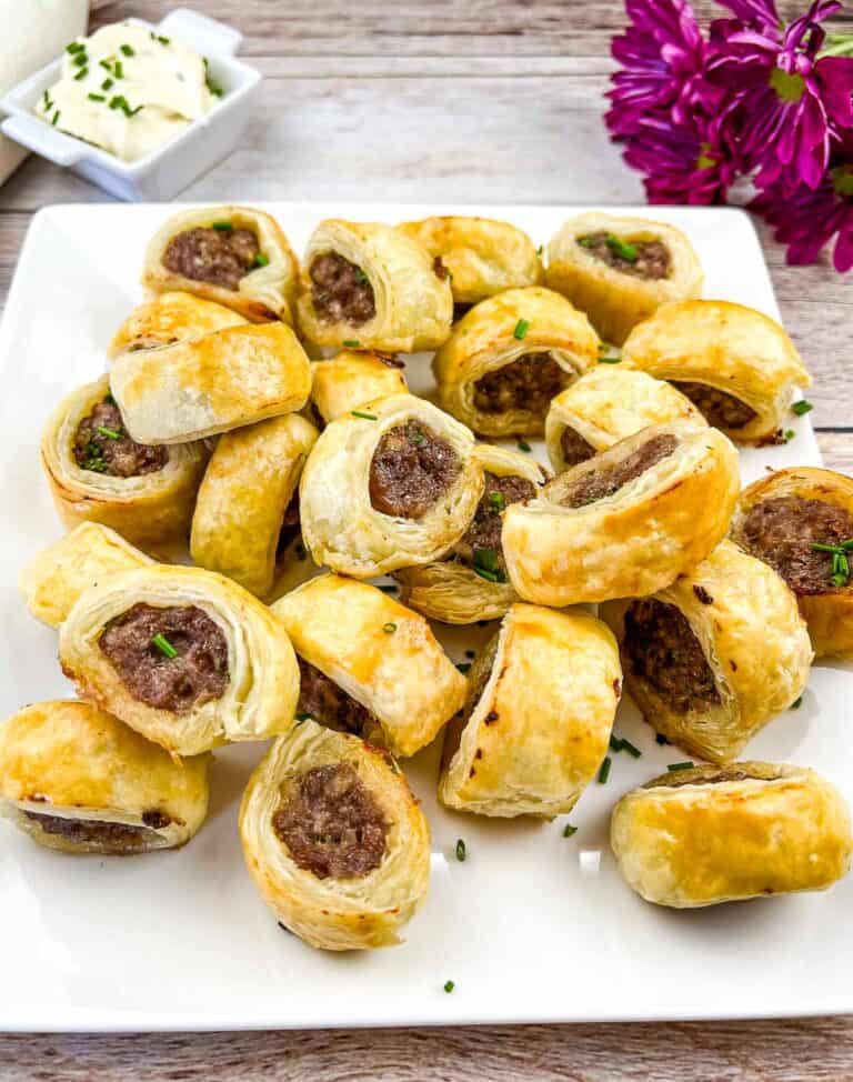 Puff pastry sausage rolls on a square plate.