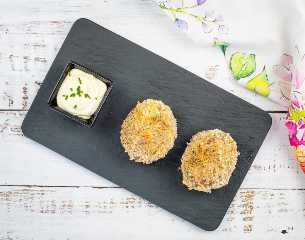 a top-down shot of 2 baked scotch eggs on a black plate.