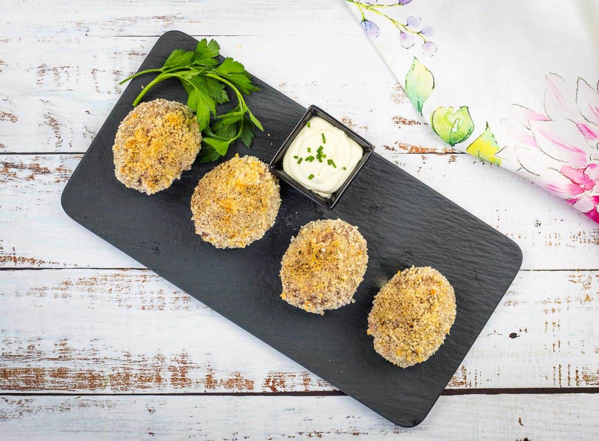 Scotch Eggs on a black plate.