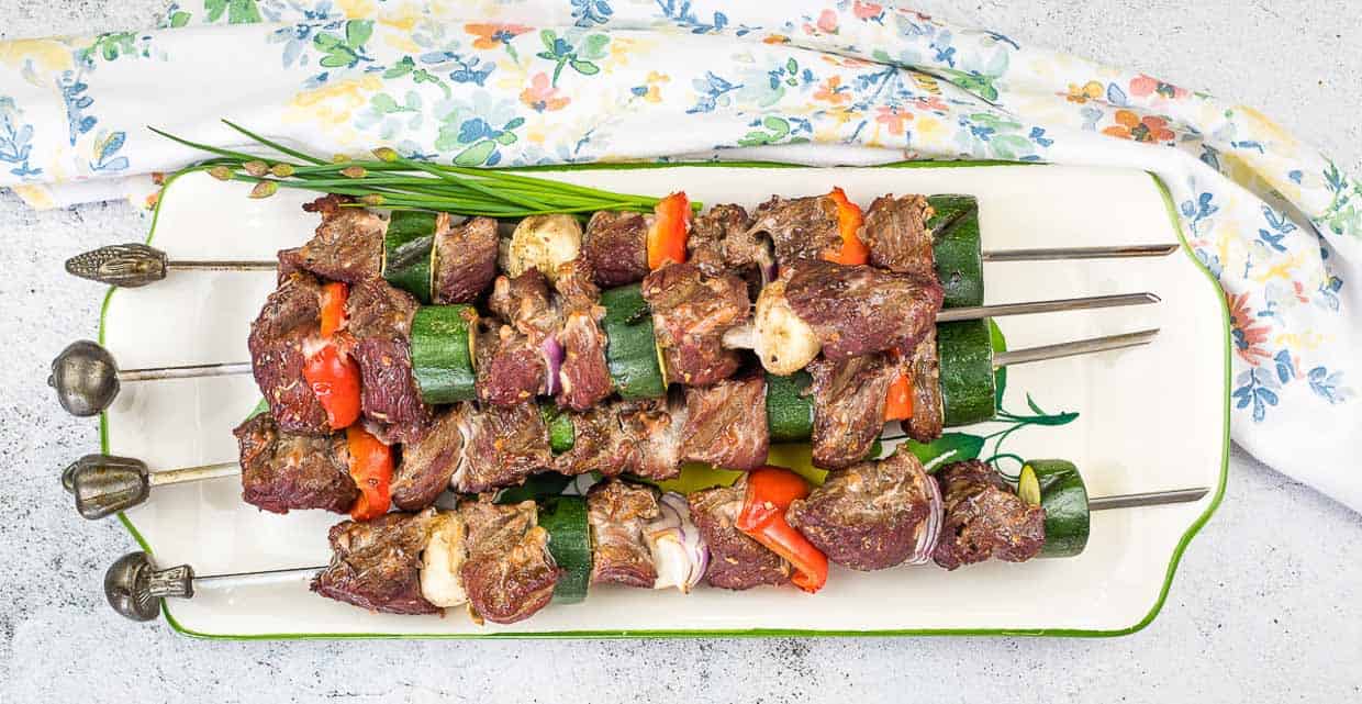 Kefta Beef Kabobs stacked on a white platter.