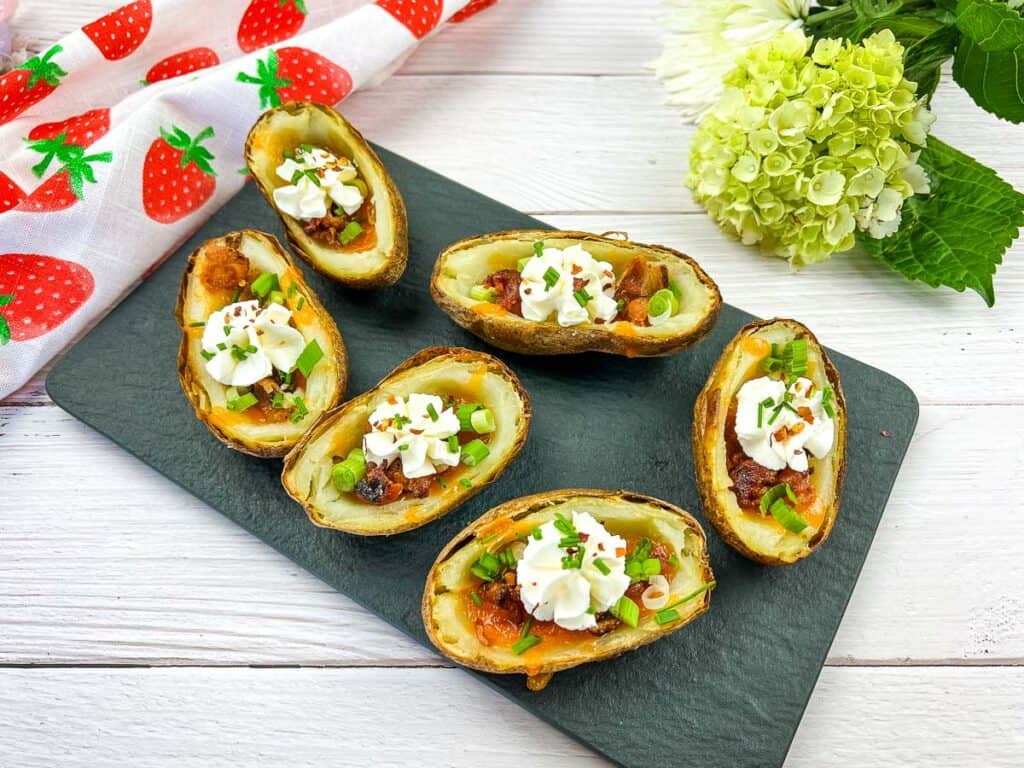 A horizontal shot of Baked Potato Skins on a black platter.