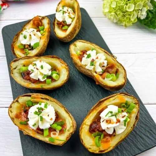 Fully loaded Baked Potato Skins on a black platter.