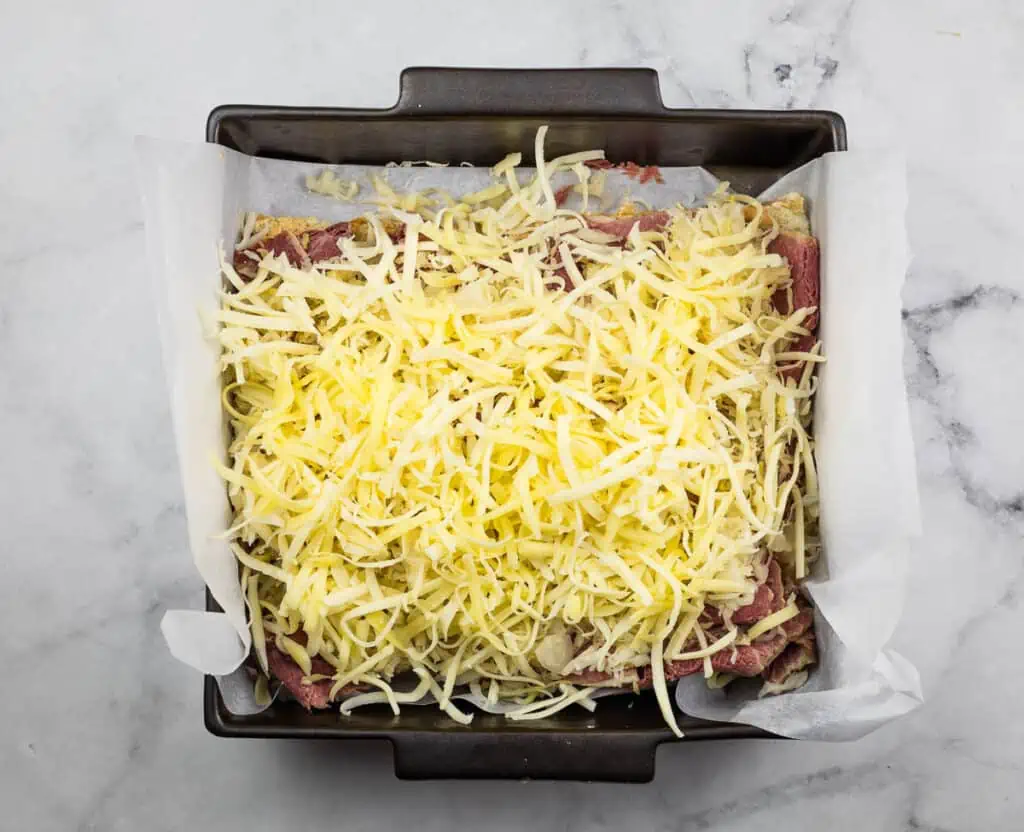 Sliders topped with cheese in a baking dish.