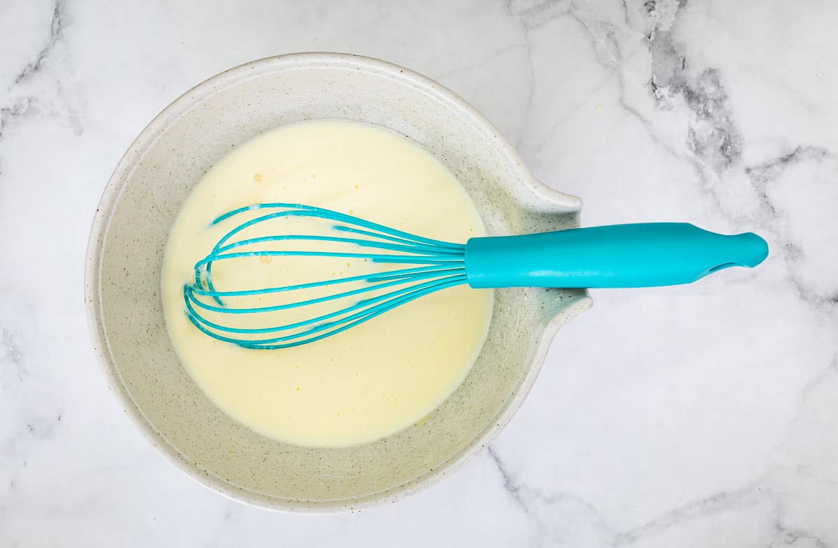 Mixed wet ingredients in a bowl with a whisk.