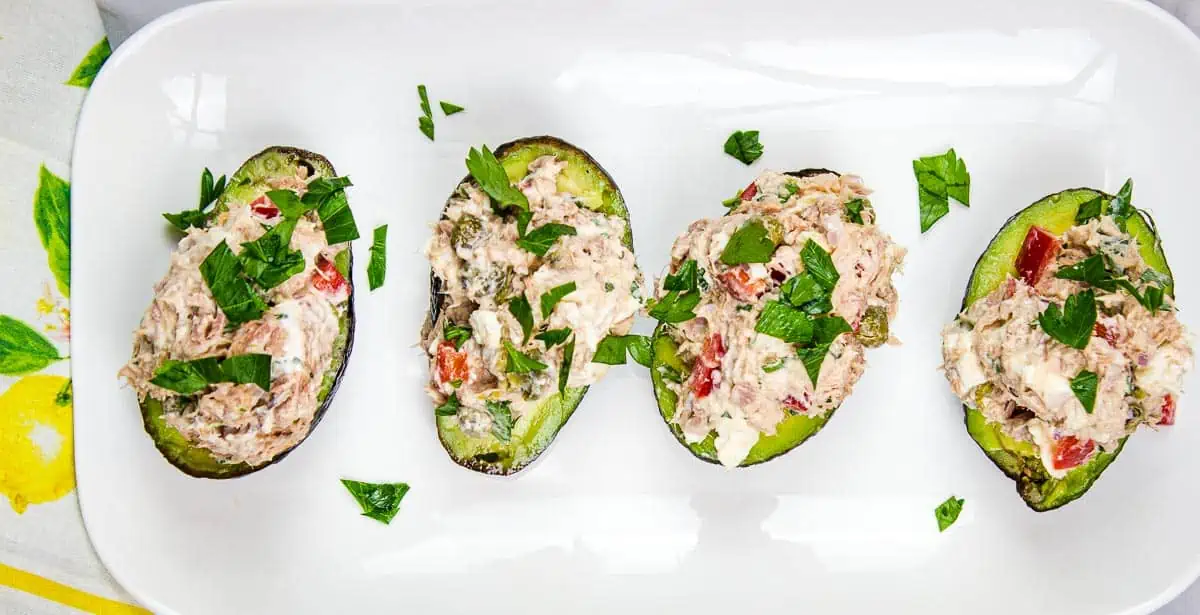 Four Mediterranean Tuna Salad stuffed avocados on a white plate.