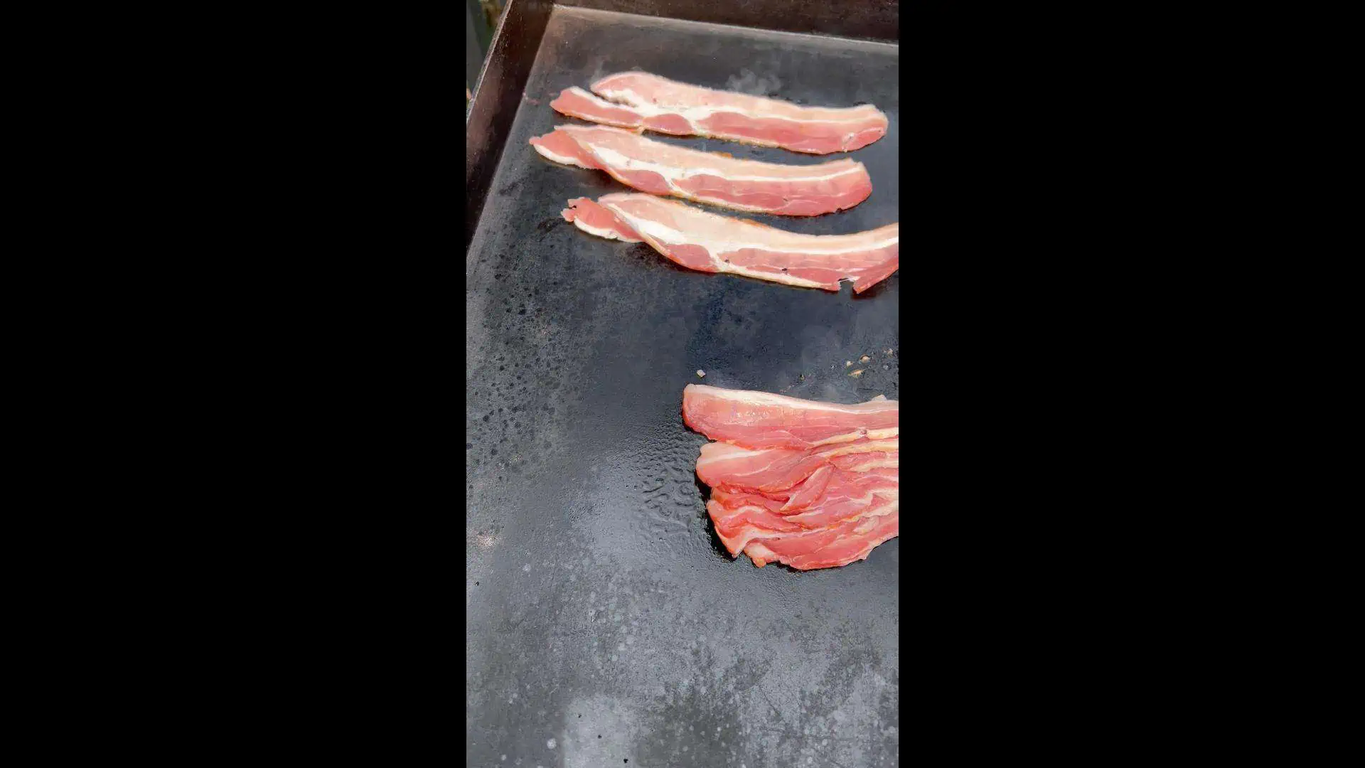 Adding bacon to the griddle.