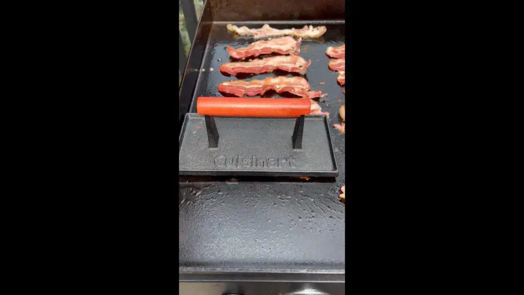 A bacon press on the bacon.