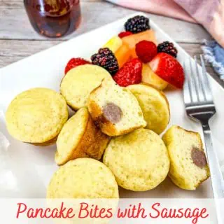 Pancake Bites with Sausage on a square plate with fruit and syrup.
